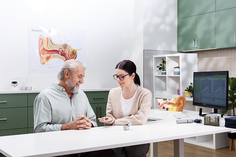 Eine Hörakustikerin berät einen älteren Mann in einem modernen Hörakustik-Studio.